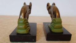 Paire de serre-livres Art Déco têtes de bélier, métal patiné et marbre noir