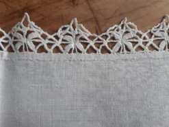 Petite nappe en fil bordée de décor au crochet fin. Années 30.