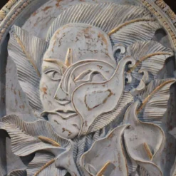 Sculpture en bas-relief, visage stylisé avec des fleurs, 20e siècle