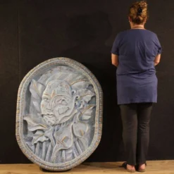 Sculpture en bas-relief, visage stylisé avec des fleurs, 20e siècle