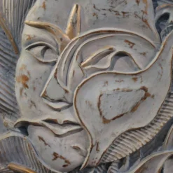 Sculpture en bas-relief, visage stylisé avec des fleurs, 20e siècle