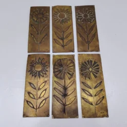 Six plaques de propreté, décor fleurs, laiton